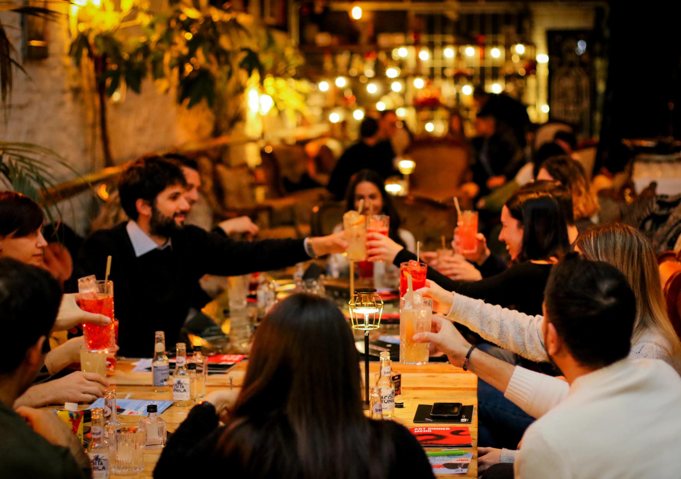 Gruppo di amici seduti attorno al tavolo che ridono mentre brindano