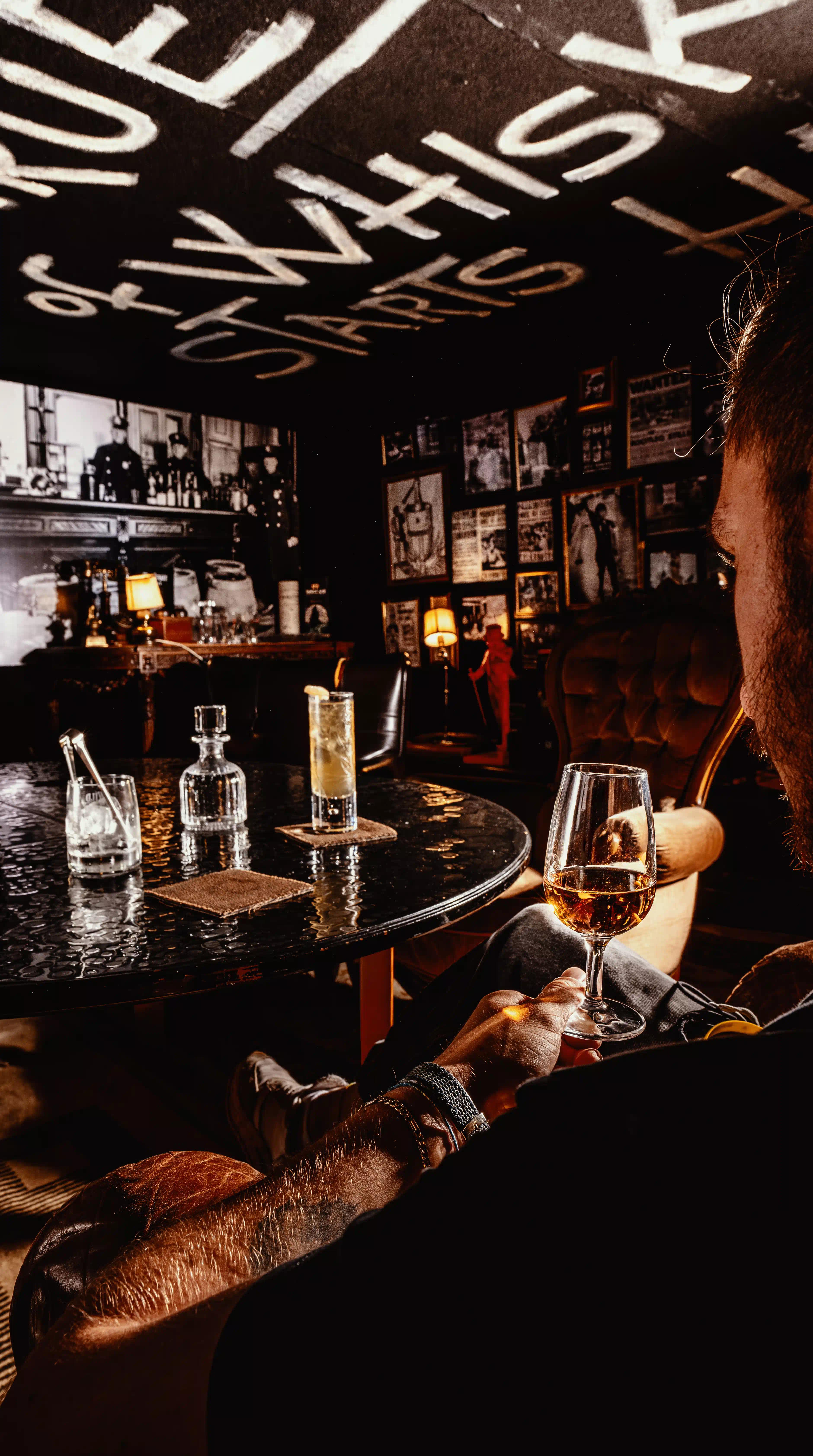 Uomo che sorseggia un whisky davanti ad un tavolo