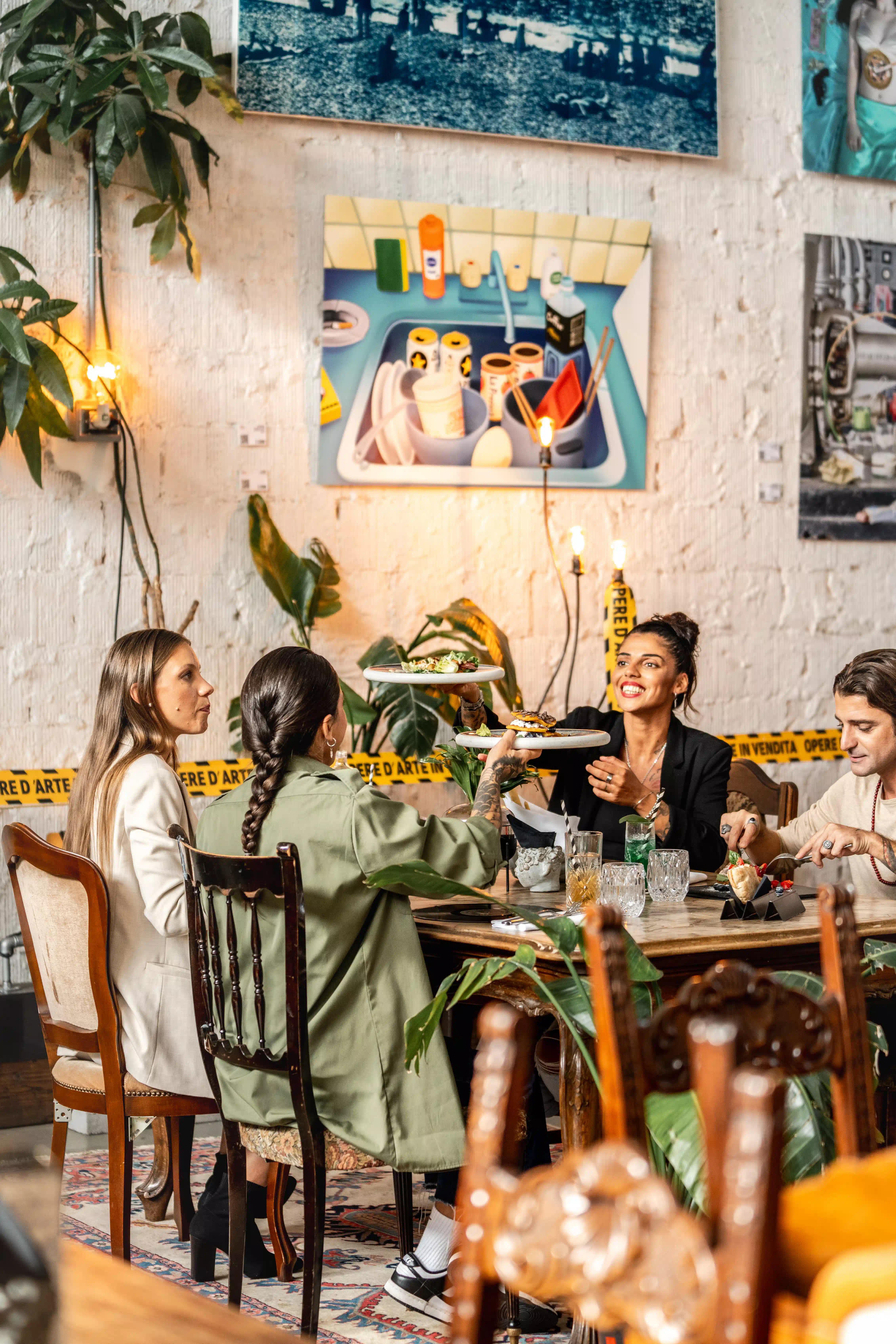 Un gruppo di persone sedute attorno ad un tavolo che ridono e mangiano