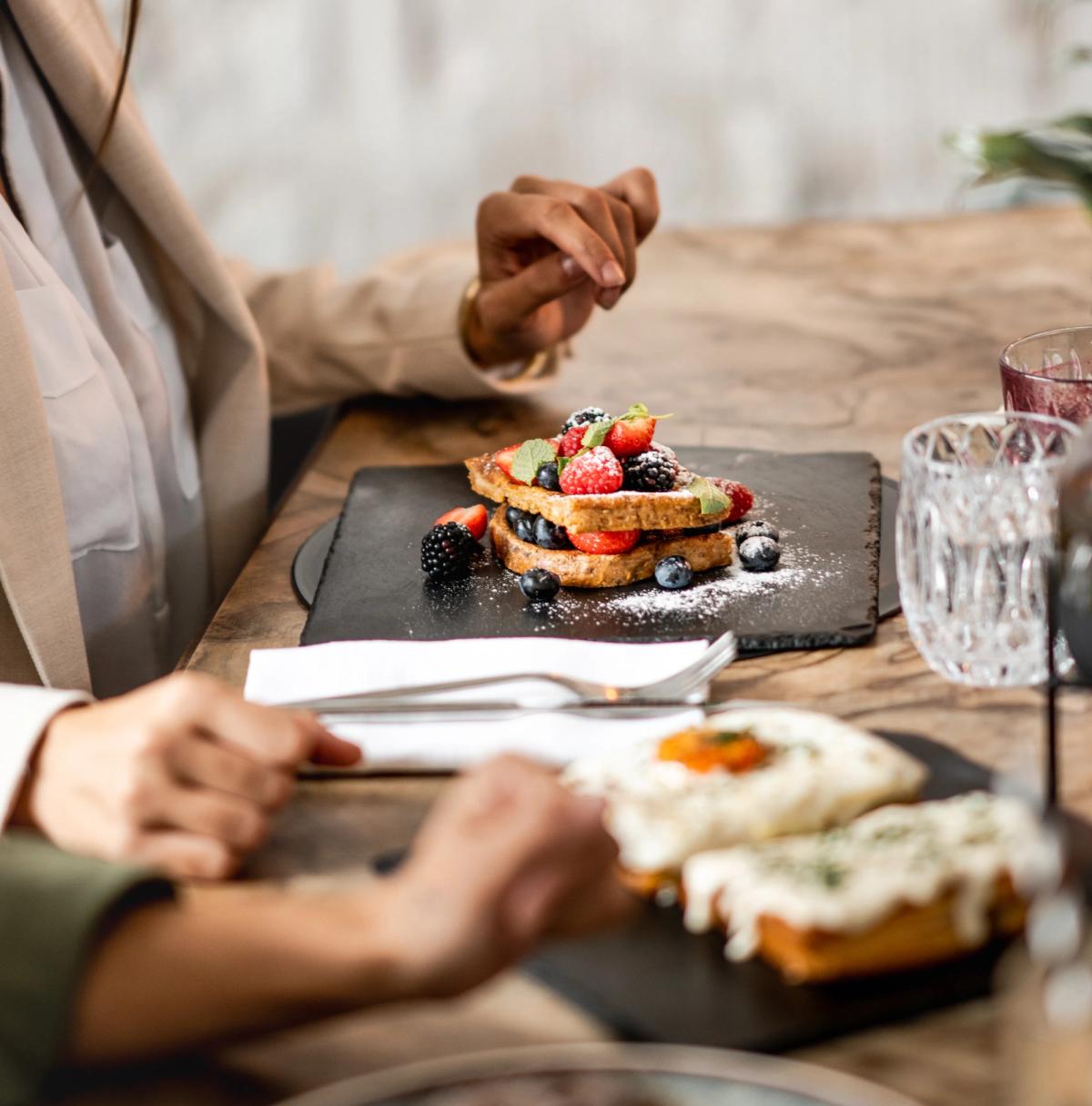 Una ragazza che ride davanti a dei pancakes con i frutti di bosco