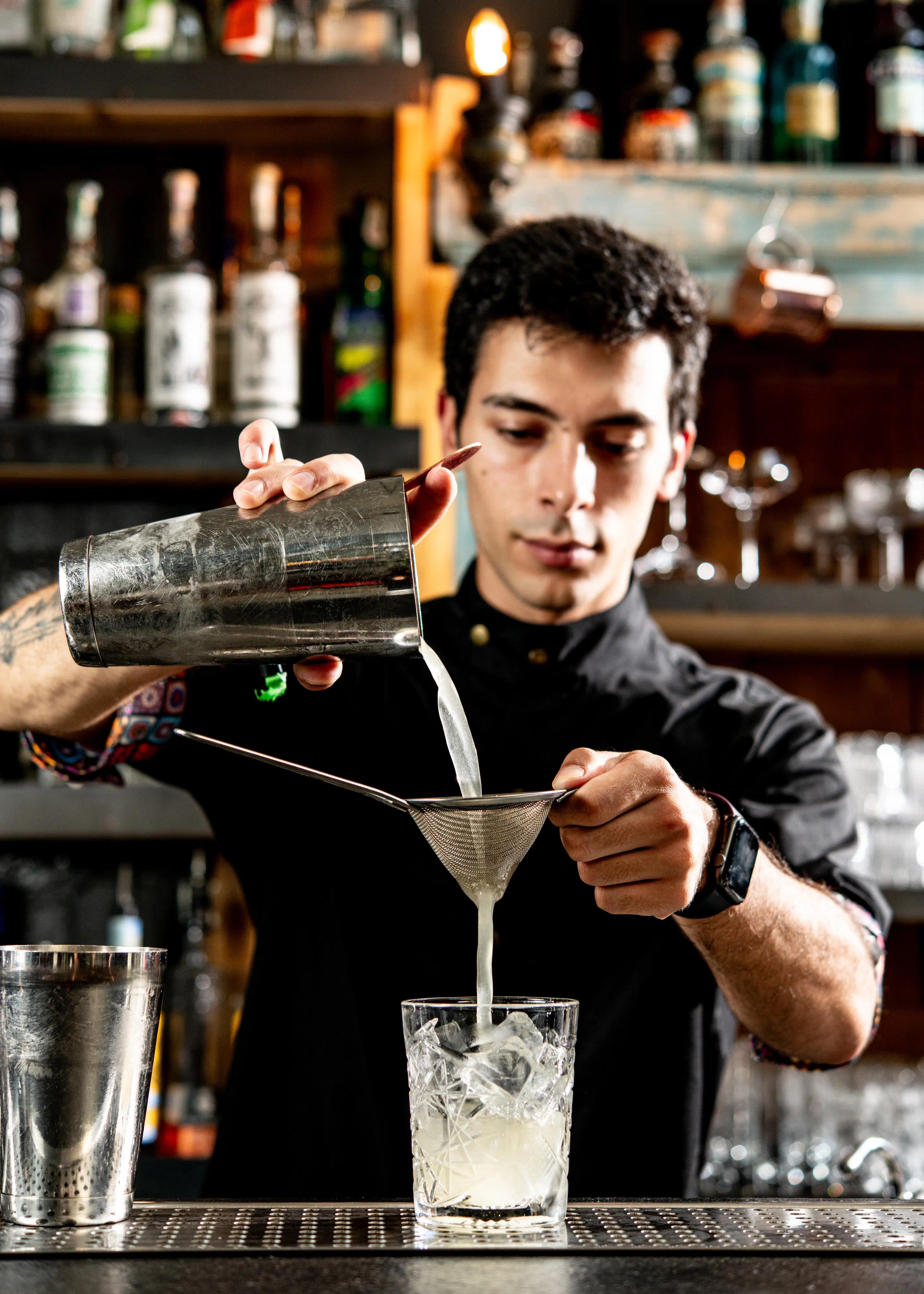 Barman che sta filtrando un drink da uno shaker