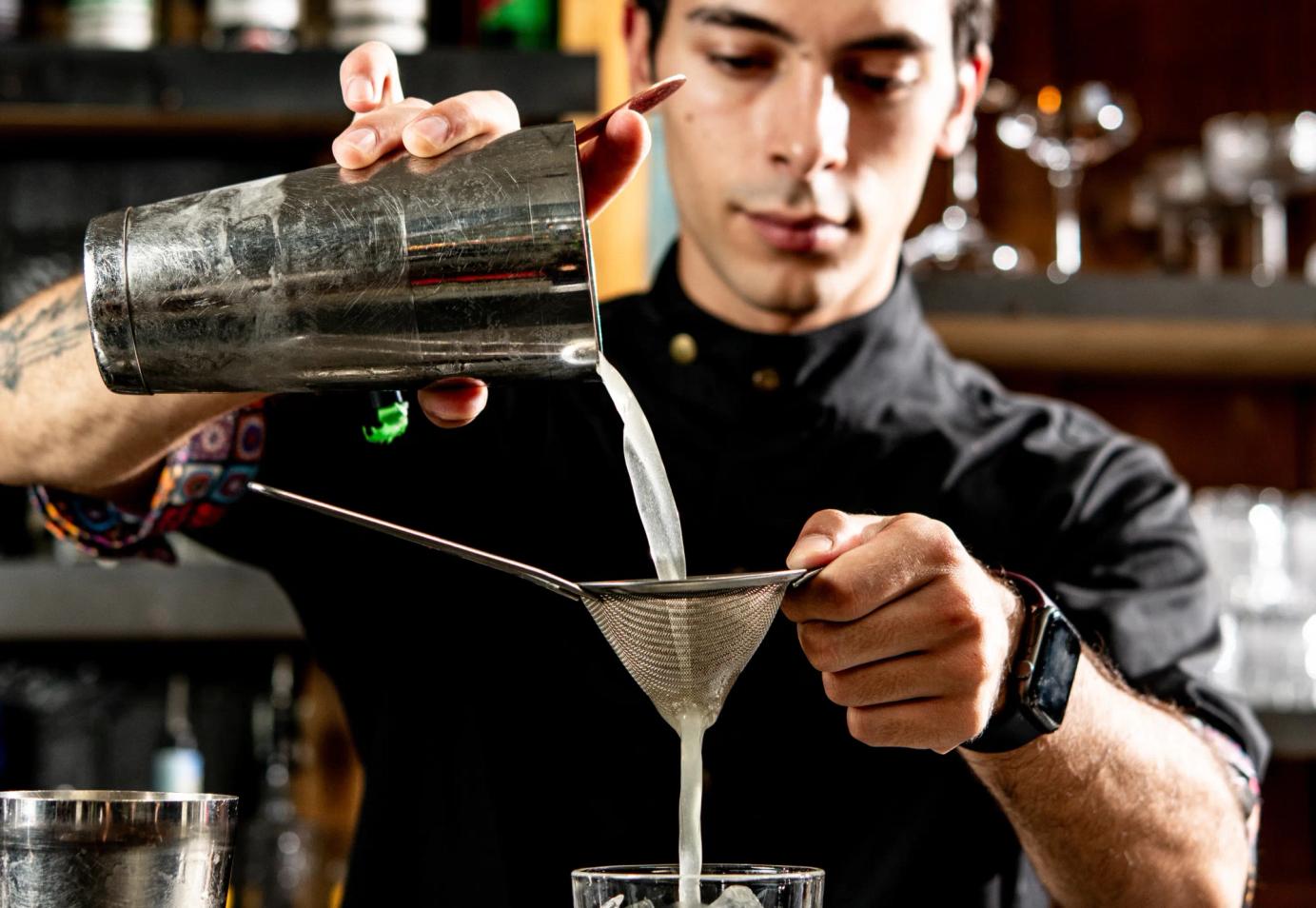 Barman che sta filtrando un drink da uno shaker