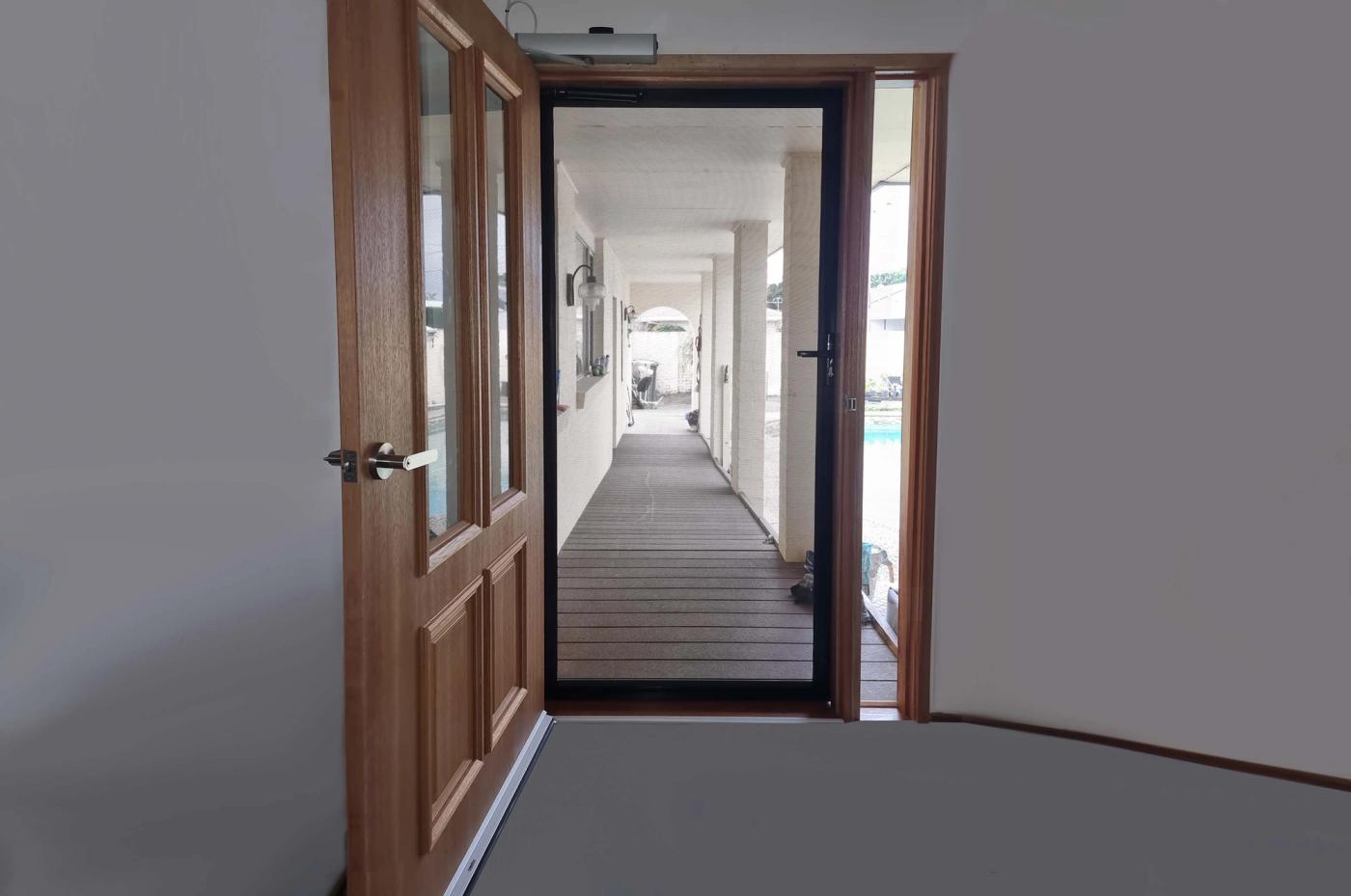 Hinged security screen door open in a hallway, showing the certified mesh and frame
