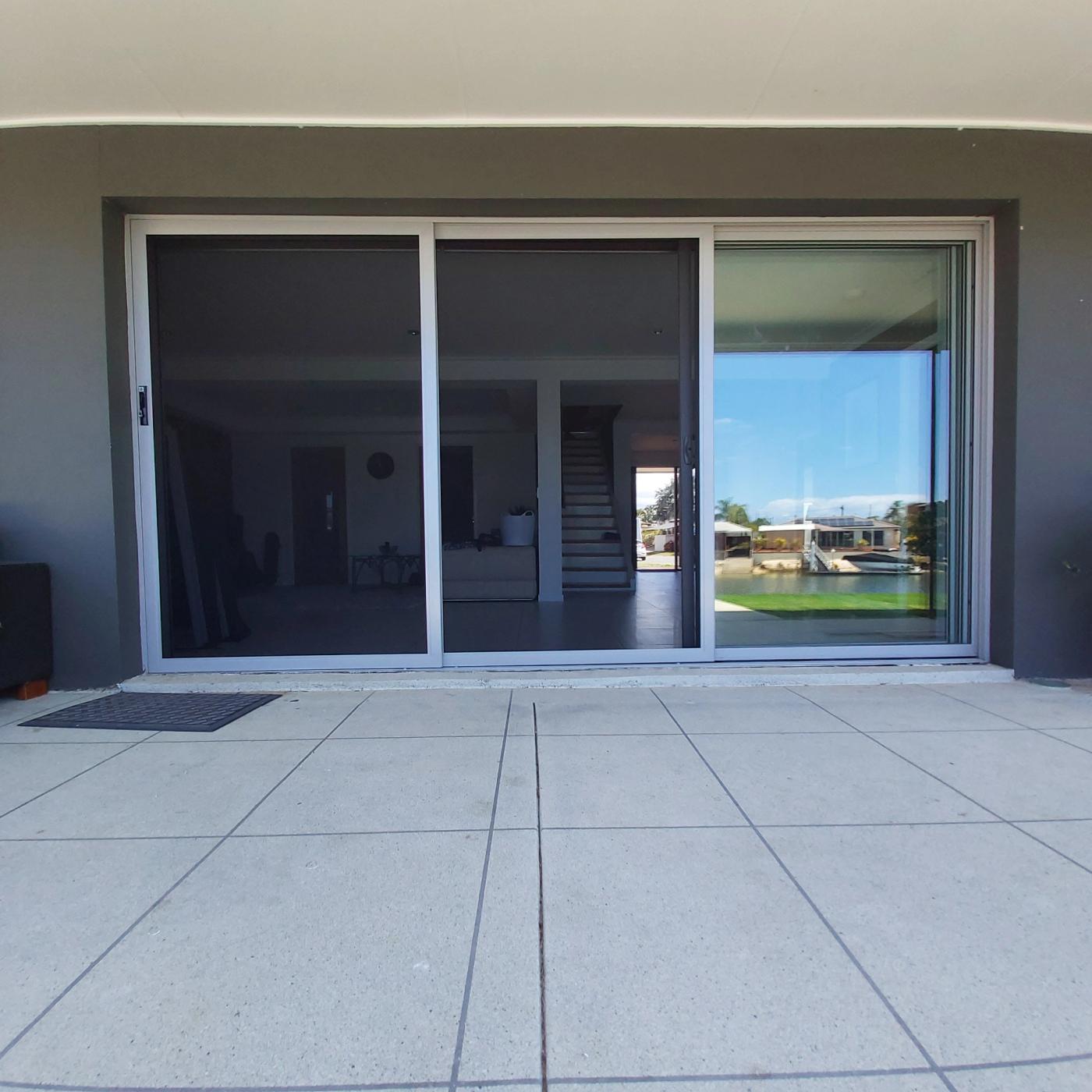 Stainless steel mesh sliding security screen door opening onto a patio