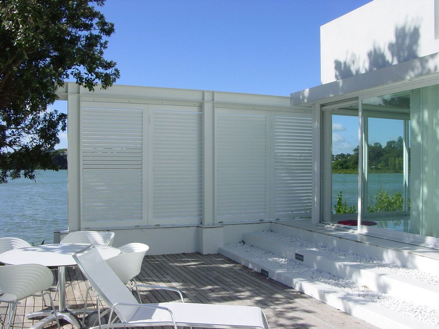 External aluminium shutters with adjustable louvres screening an outdoor entertaining area