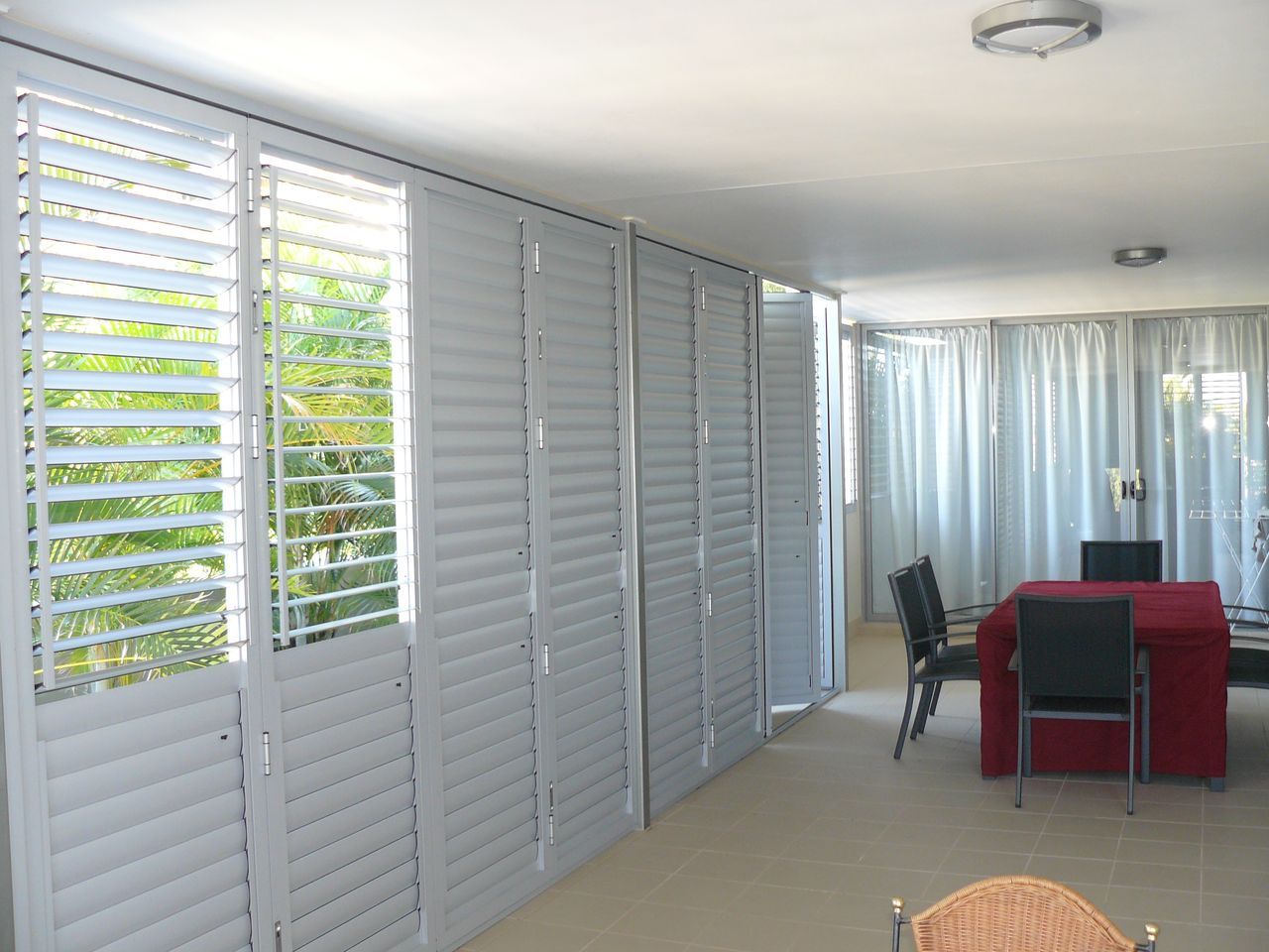 Aluminium bi-fold shutters with louvres open along the side of a room