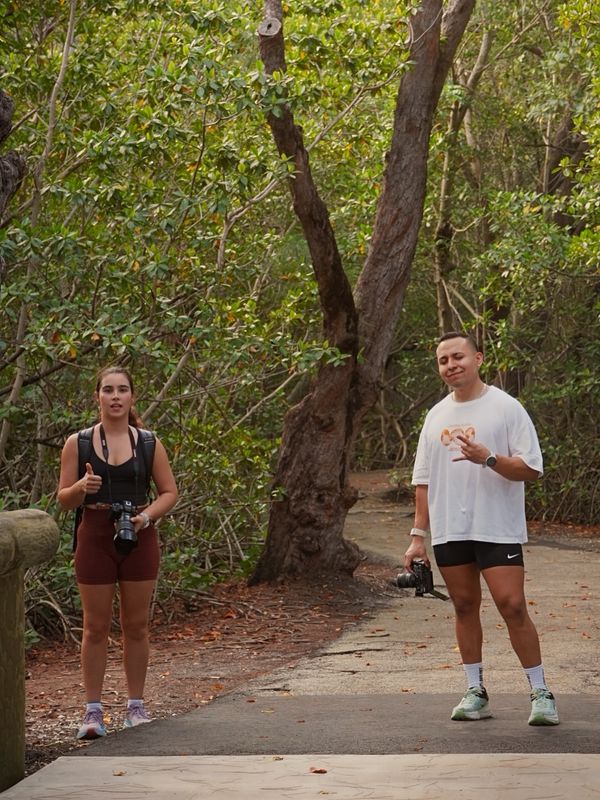 Two people carrying cameras pause on a shaded trail during Roots Fly High.