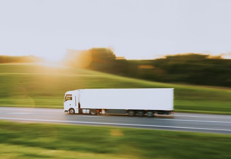 Semi truck driving down a rural highway, representing freight carrier outreach and load booking