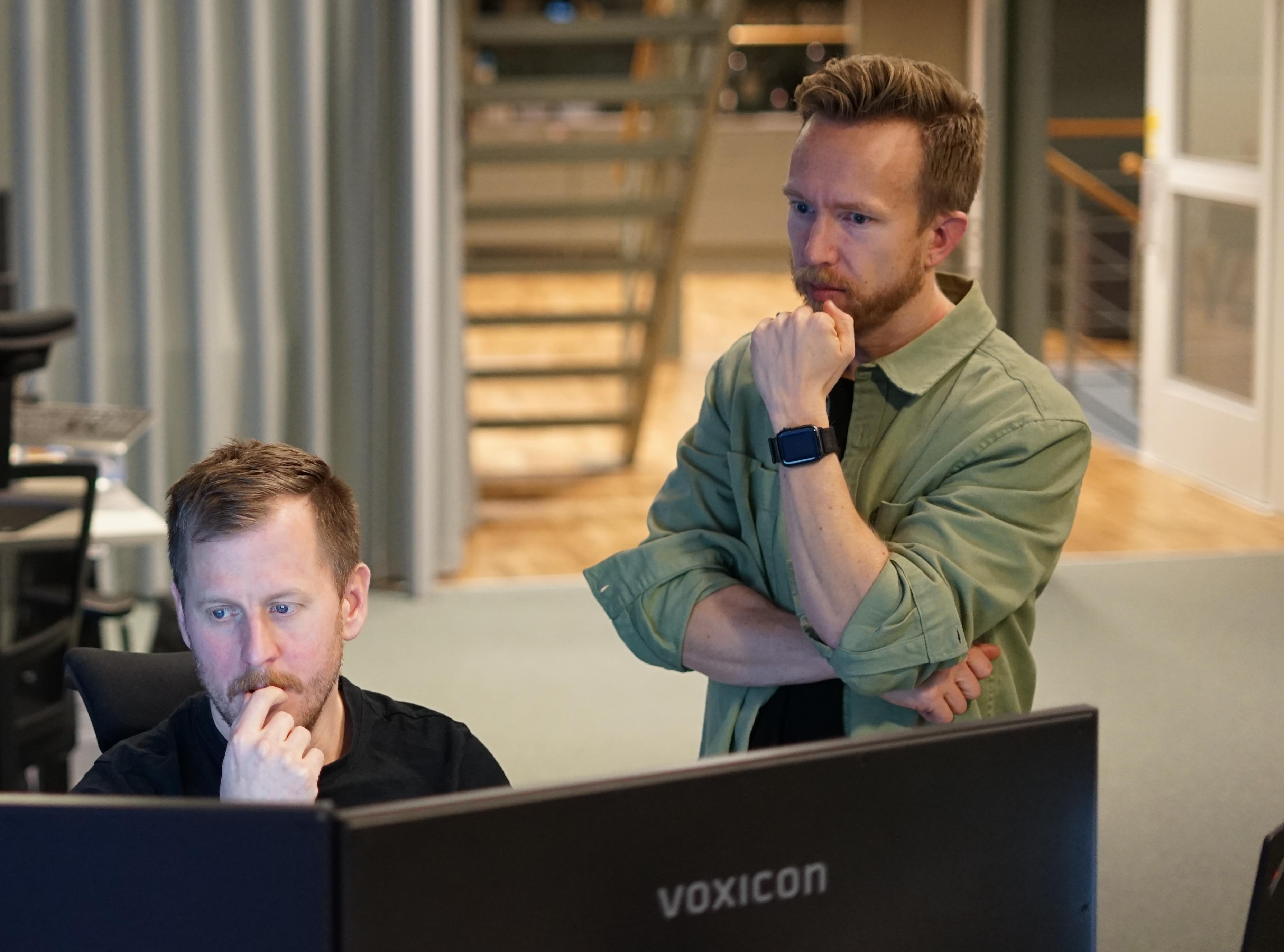 Två män samtalar framfor datorn