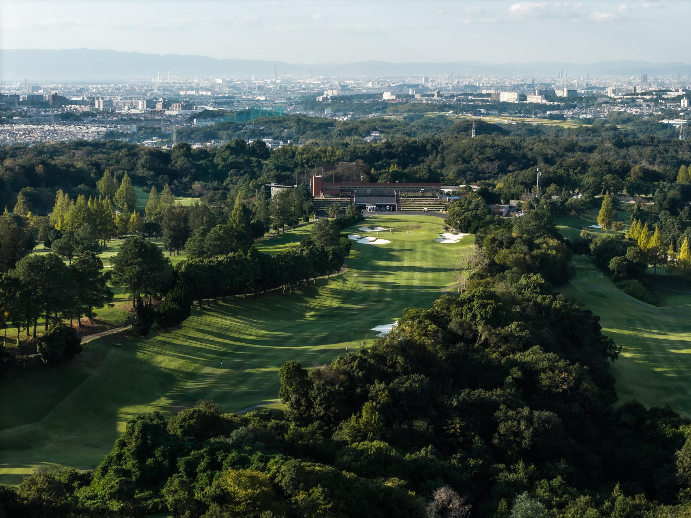 Aerial view down a tree-lined fairway to the clubhouse