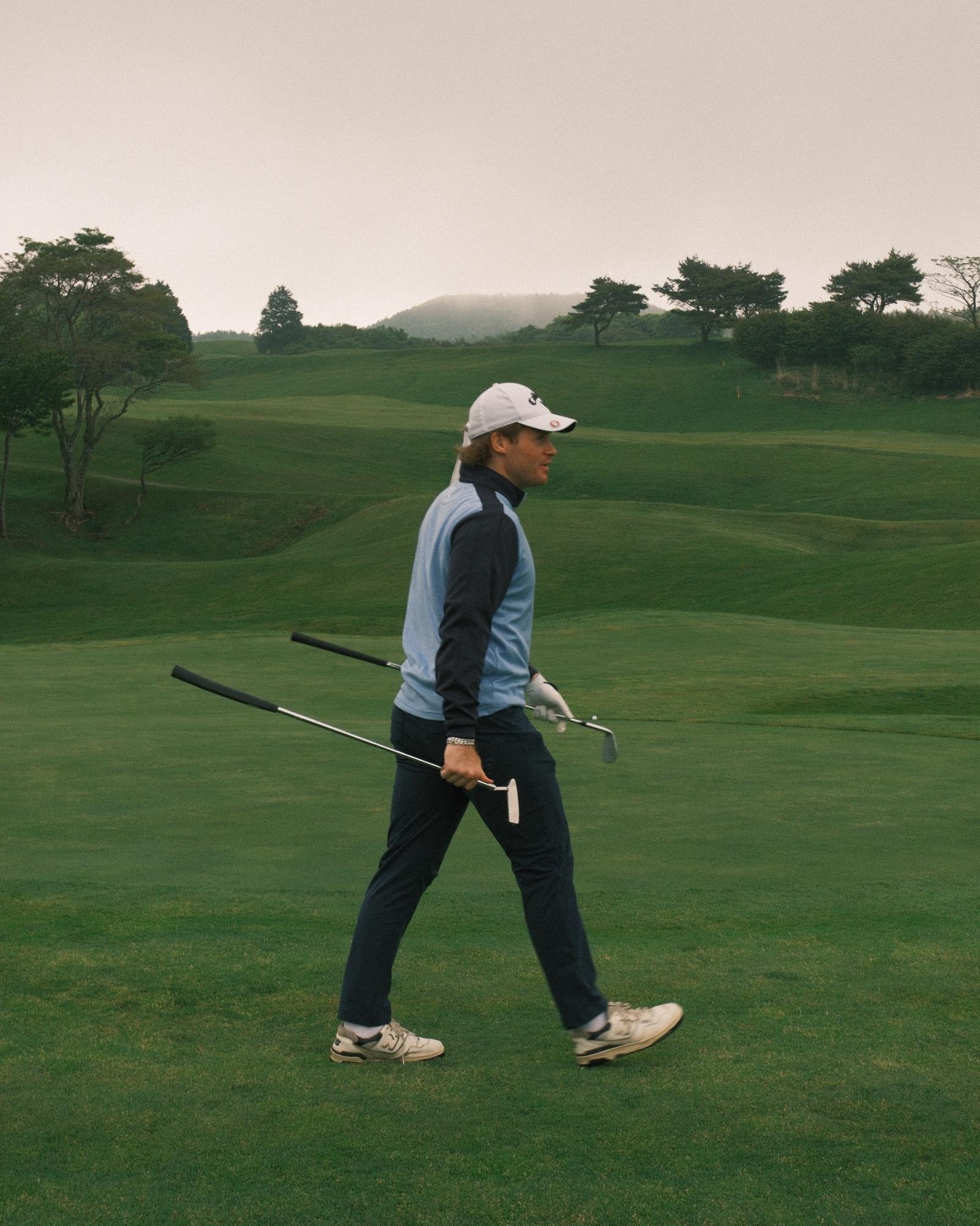 Walking off the green, putter and wedge in hand