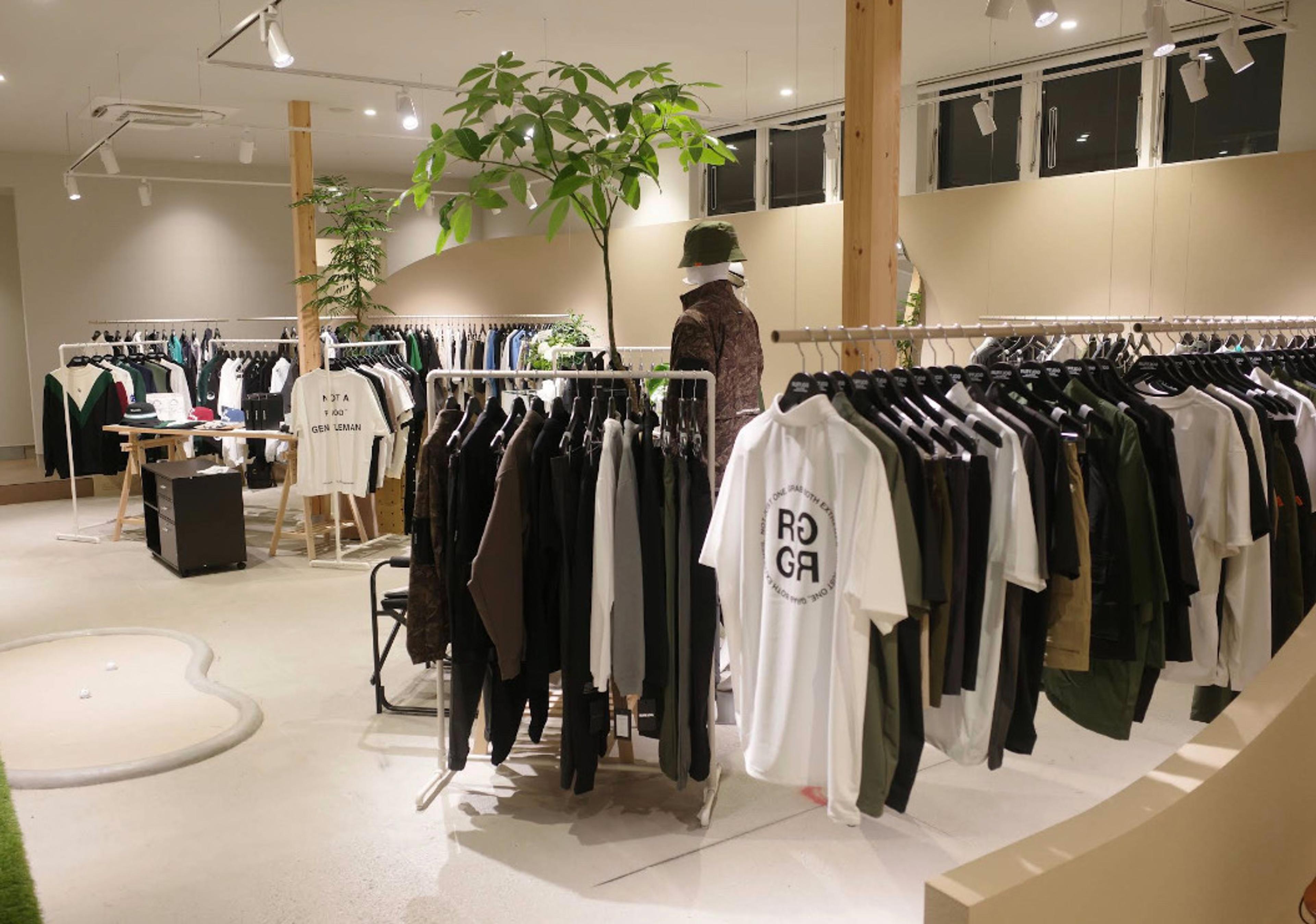 Inside RUFFLOG Kanazawa — golf apparel on racks with an indoor putting mat