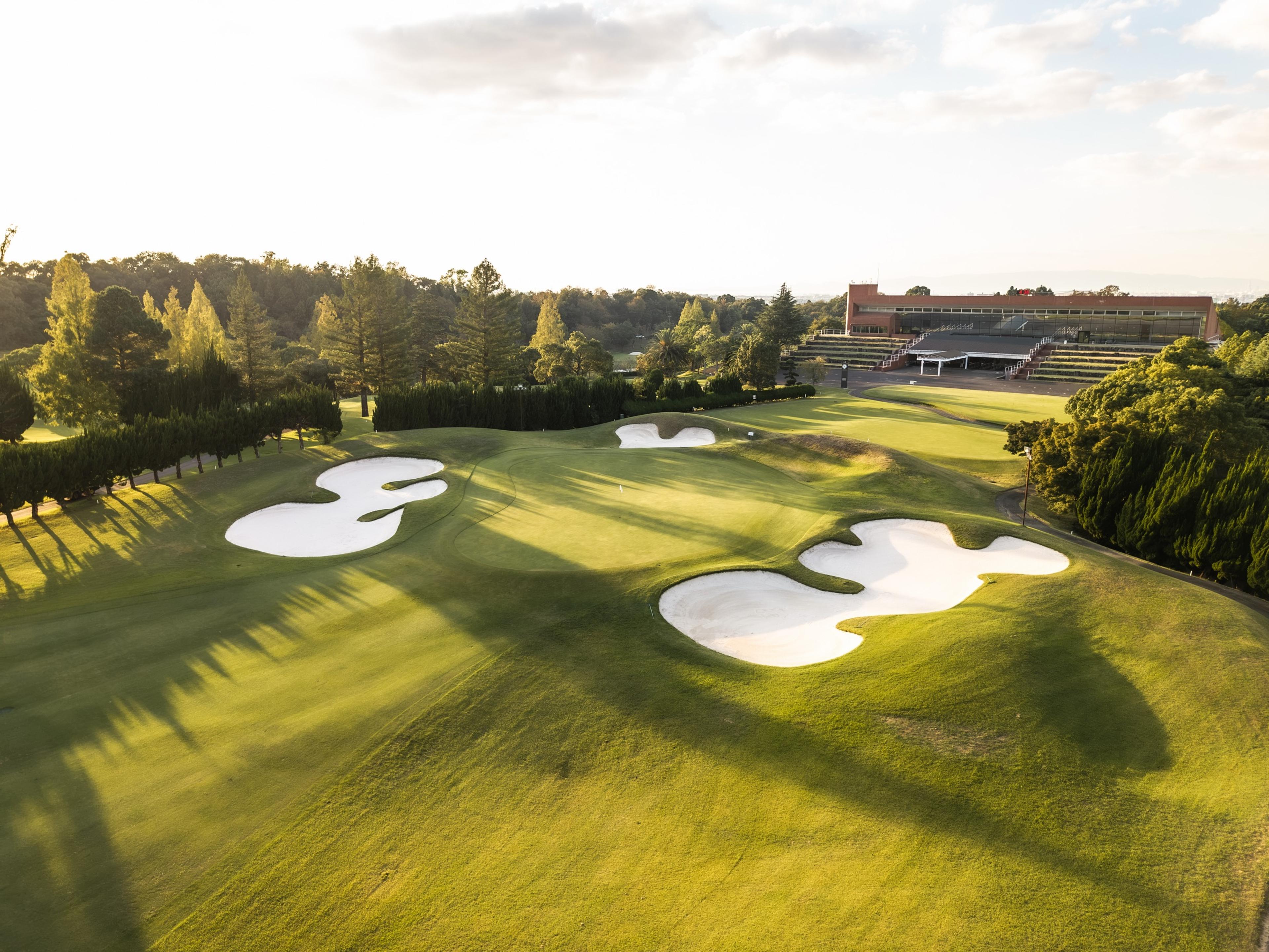 Green ringed by bunkers below the clubhouse