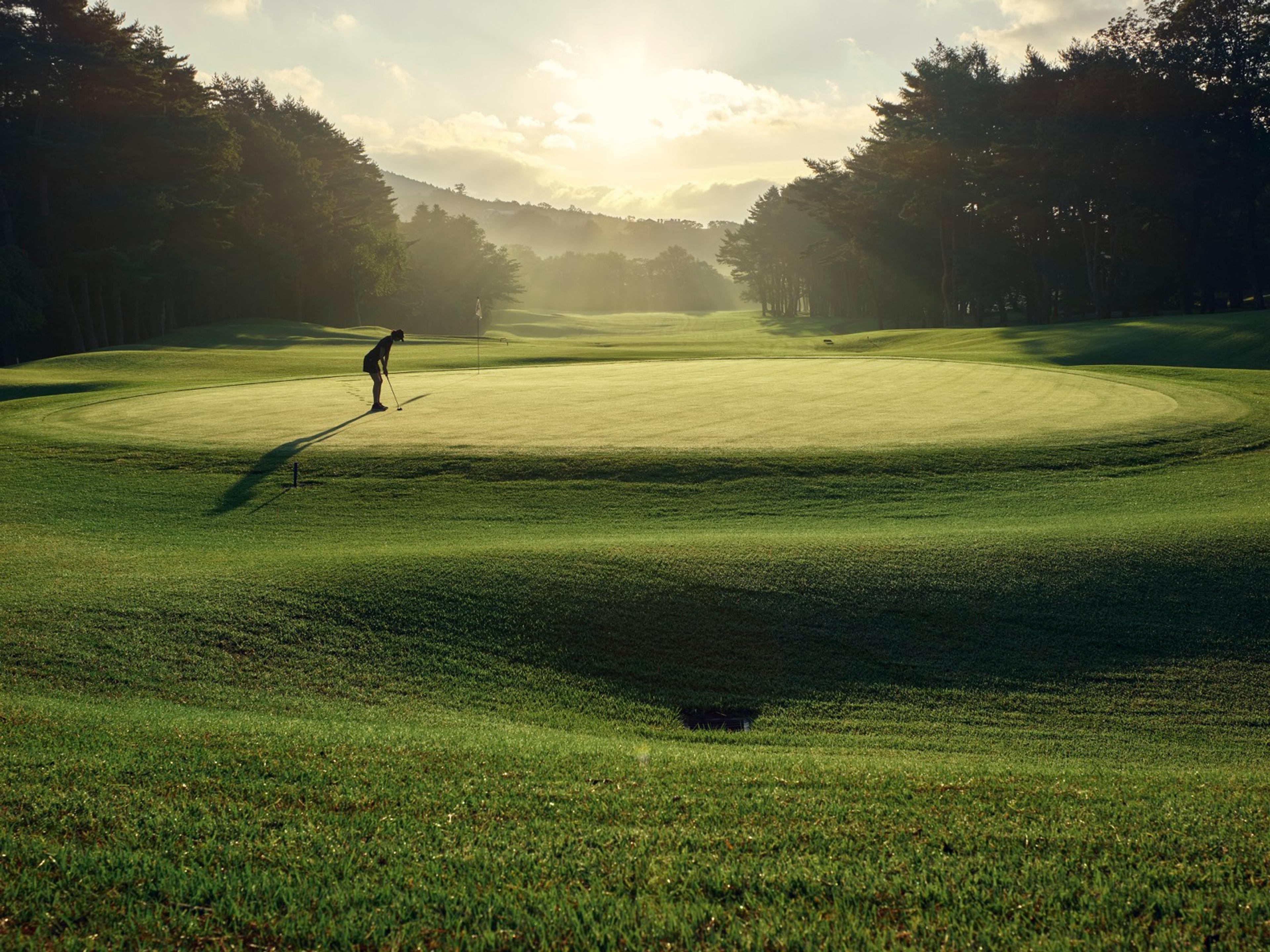 Golfer putting on a Kagosaka Course green at golden hour