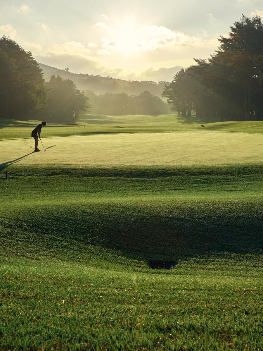 Golfer putting on a Kagosaka Course green at golden hour