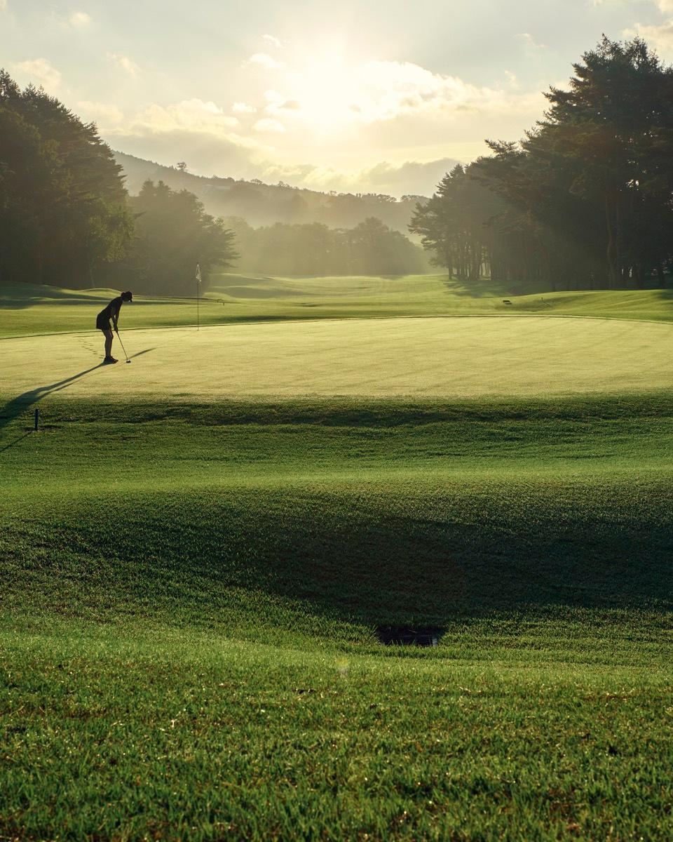 Golfer putting on a Kagosaka Course green at golden hour