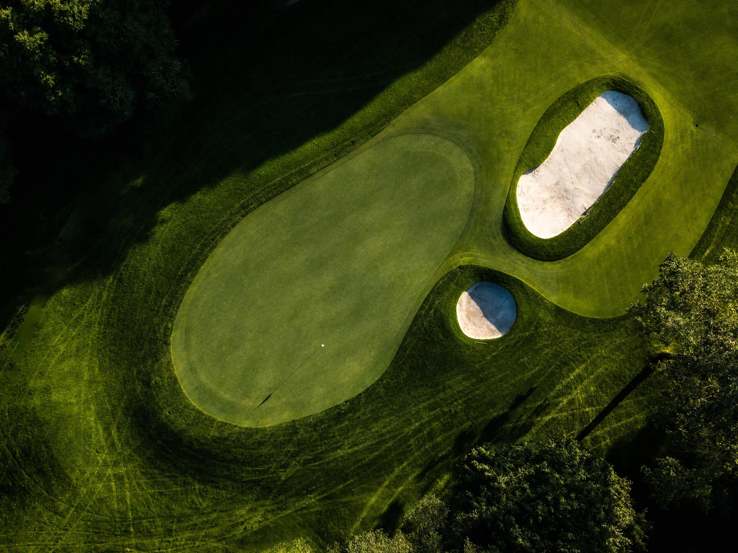 Overhead view of a green guarded by a kidney-shaped bunker and a small pot bunker