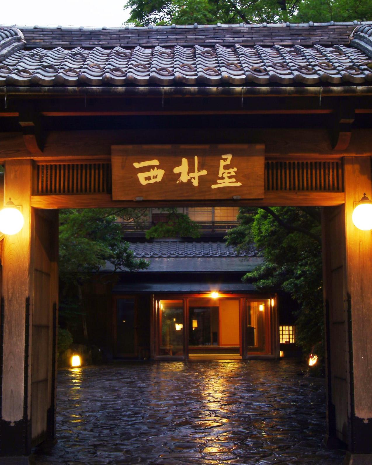 Nishimuraya Honkan — the lantern-lit entrance gate on Kinosaki Onsen's main lane at dusk