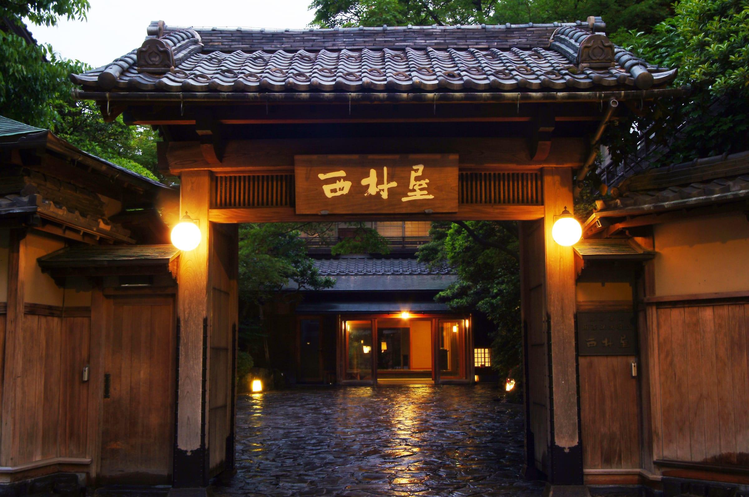 Nishimuraya Honkan — the lantern-lit entrance gate on Kinosaki Onsen's main lane at dusk
