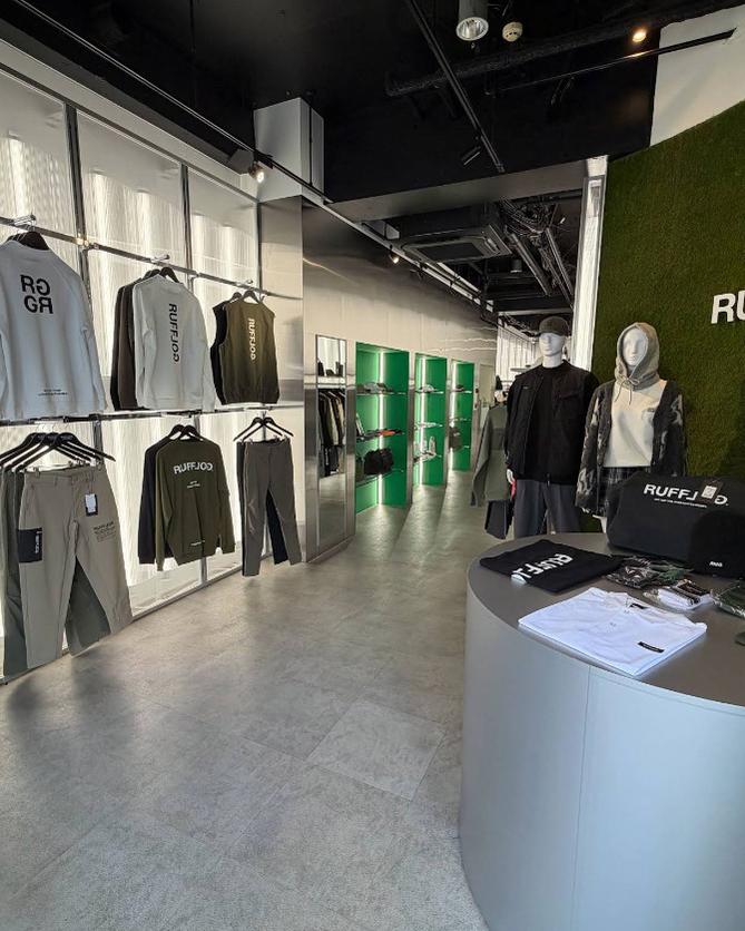 Inside RUFFLOG Osaka — apparel racks and the moss-green logo wall