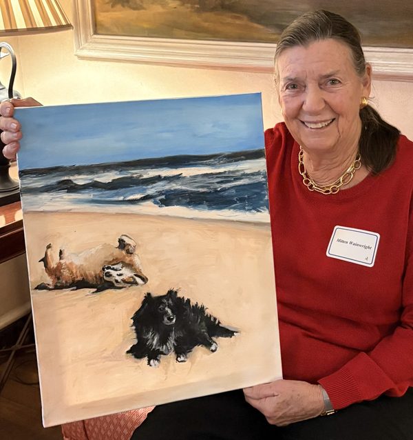 Mitten holding the painting of Dixie and Millie on the beach.