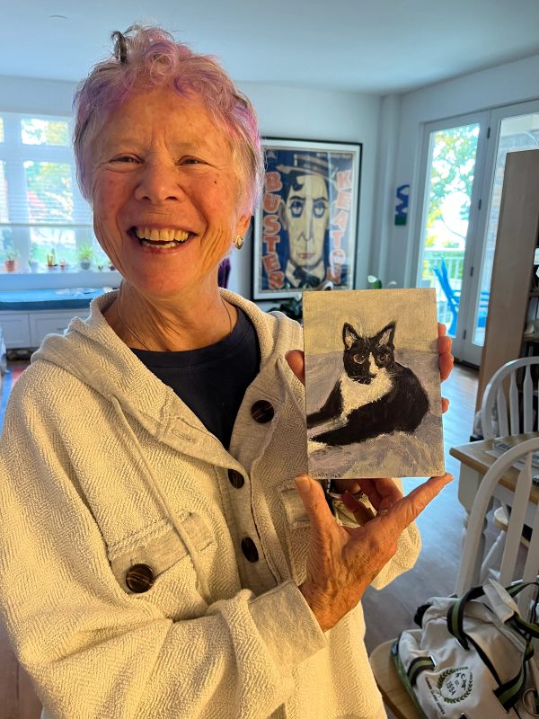 Stella Pence holding a painting of a black and white cat.