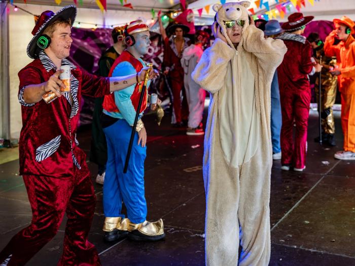 Verklede gasten dansen met silent disco koptelefoons in de feesttent