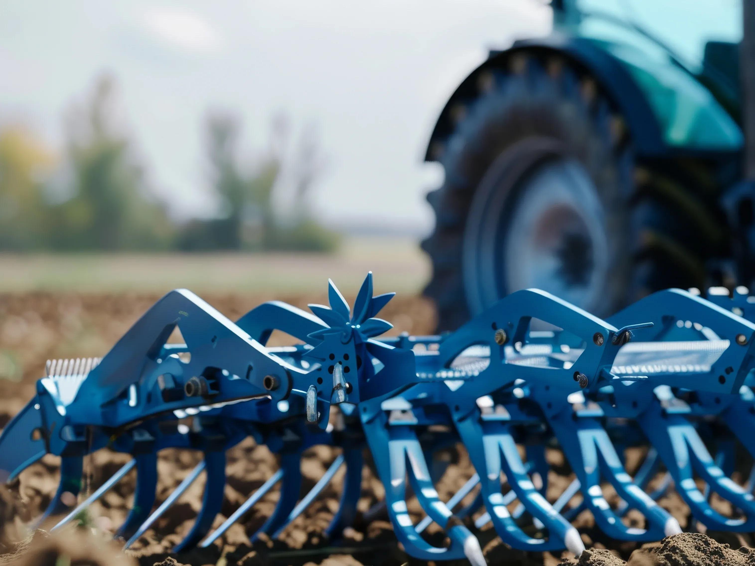 Blue agricultural cultivator attached to a tractor in a field