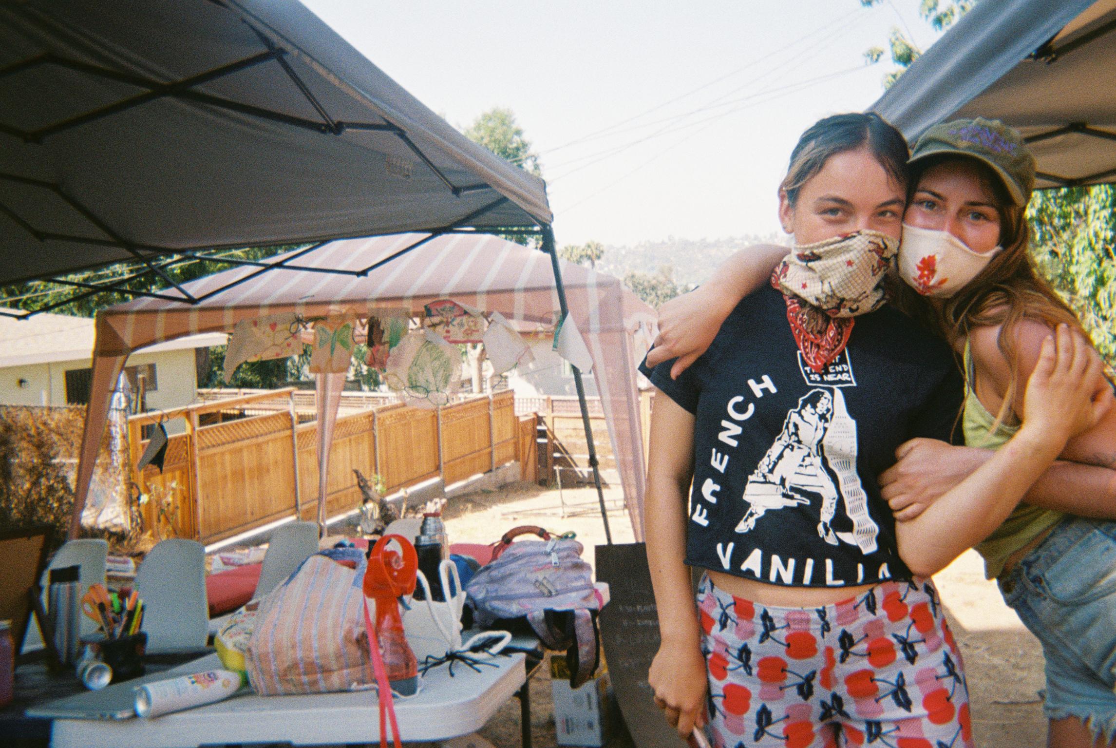 Two people wearing masks and giving each other a side hug