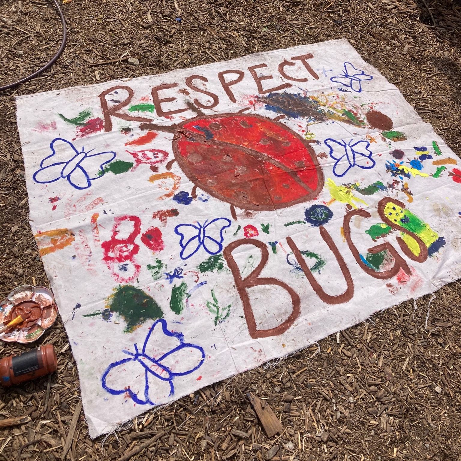 A collaboratively-painted banner that says "Respect Bugs" with a big ladybug in the middle