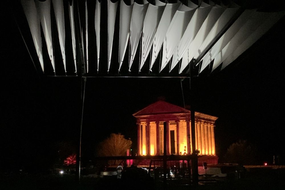 Custom-built black steel DJ canopy with white fabric shade panels, covering a DJ setup at an outdoor festival in the Armenian mountains.