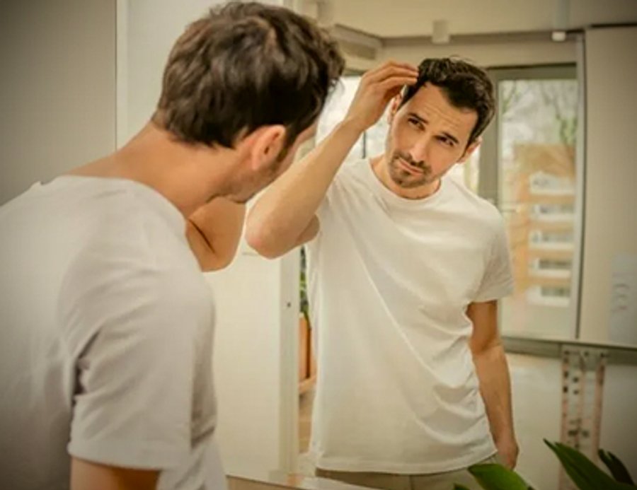 Man styling his hair in a mirror