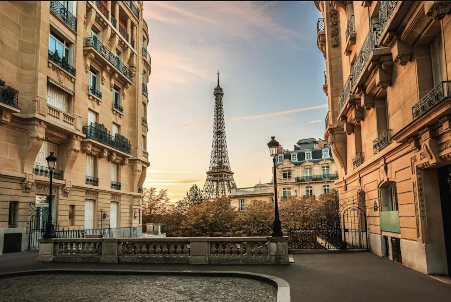 A Paris street at dusk, the Eiffel Tower beyond