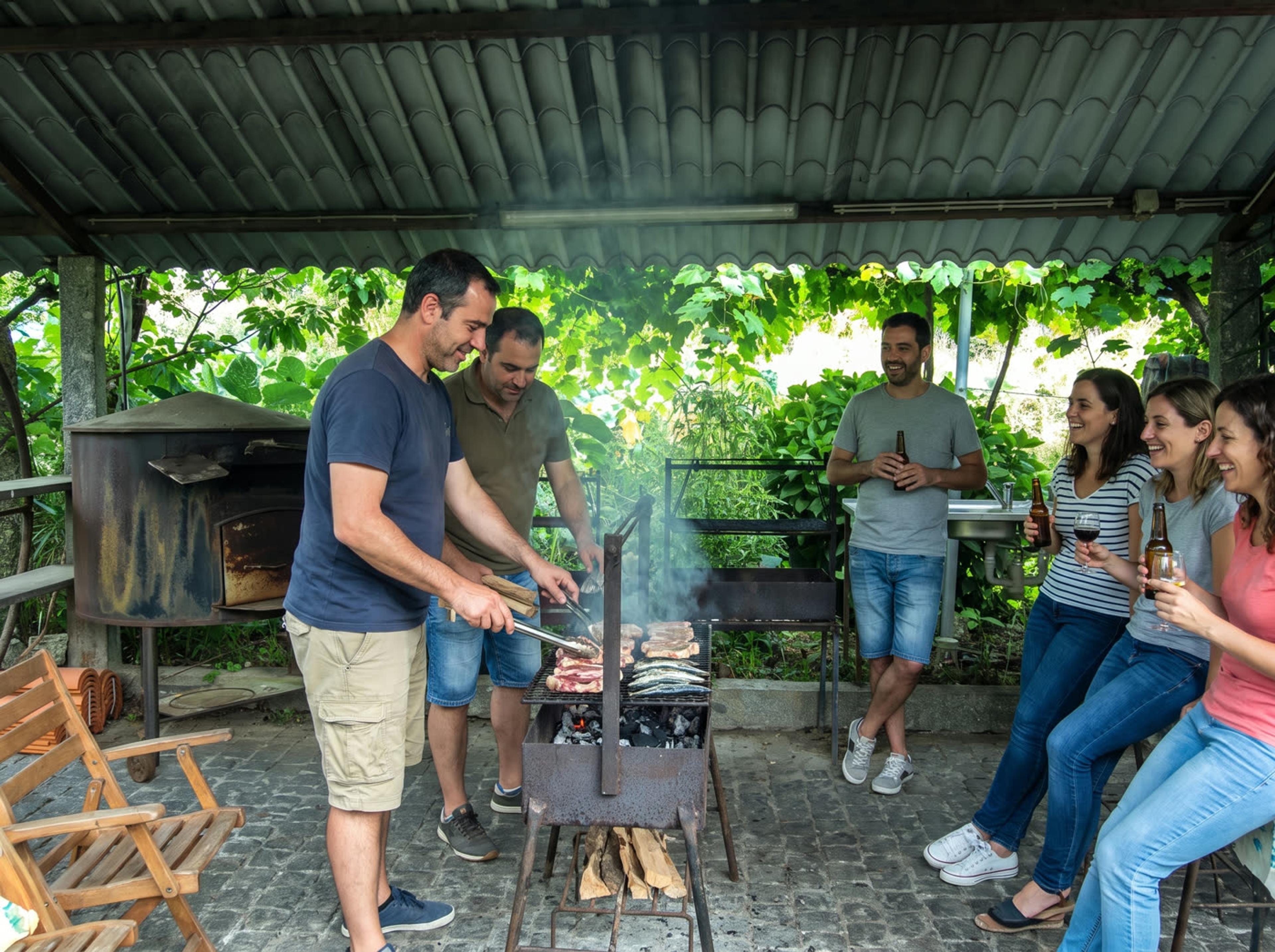 Amigos a preparar um churrasco na zona de grelhados coberta da quinta