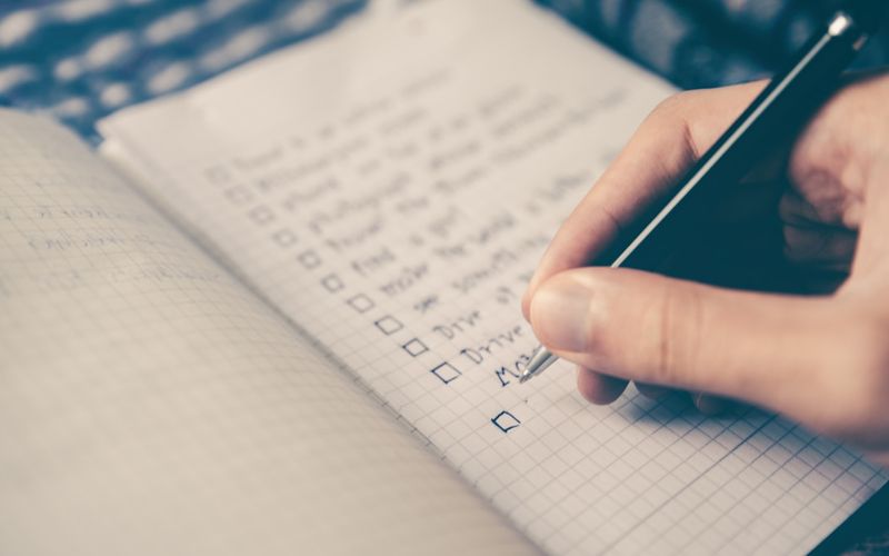 A checklist notebook with a pen on a wooden desk