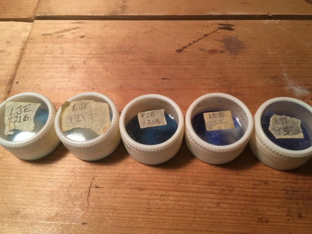 Row of pots filled with different shades of blue enamel powder