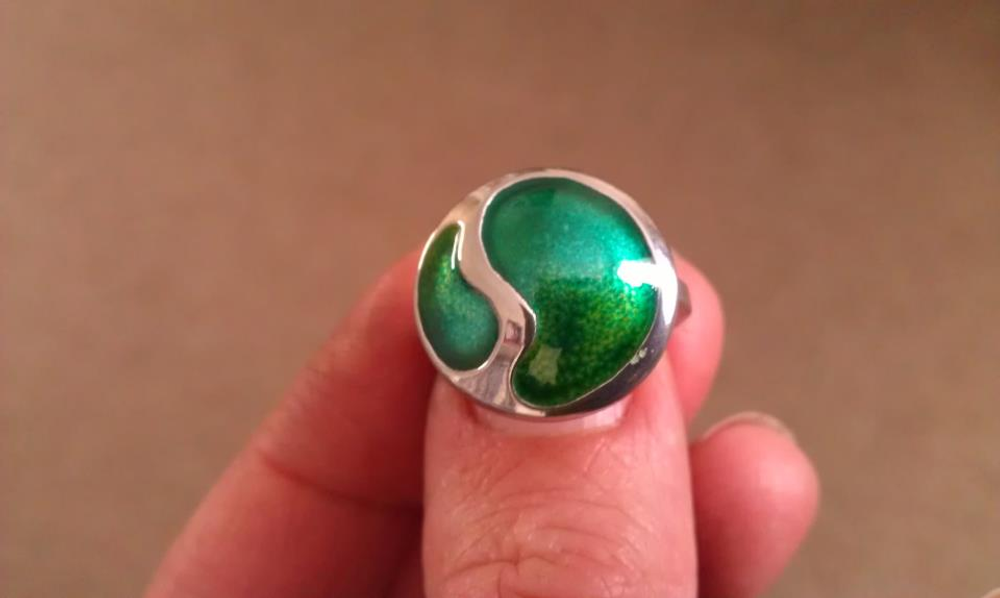 Finished silver and green enamel ring being held