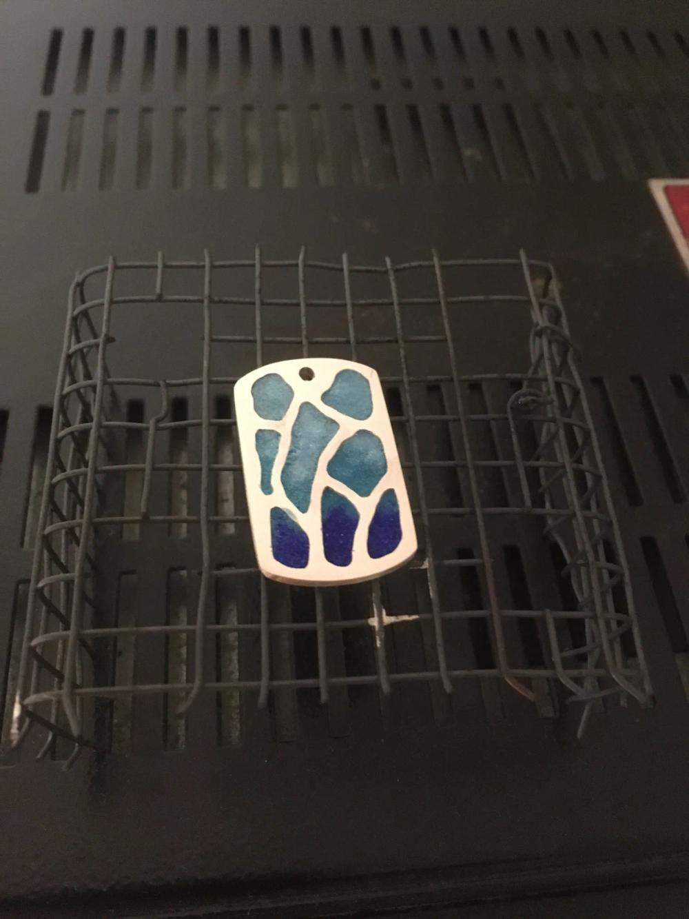Fired blue enamel and silver pendant on wire cooling rack