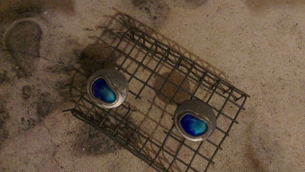 Silver cufflinks with blue enamel sat in wire cooling rack