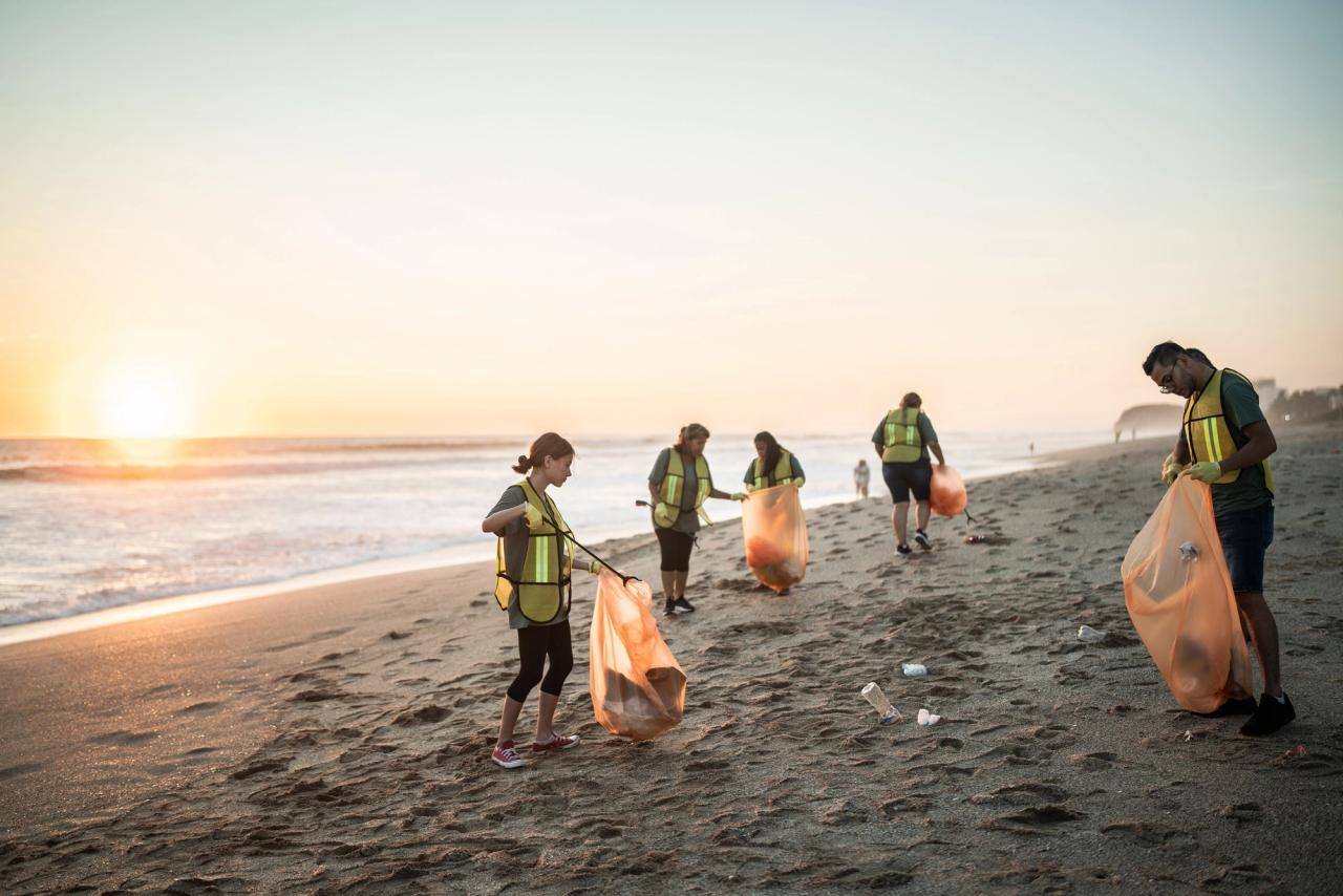 A group of people doing a beach clean up at sunset