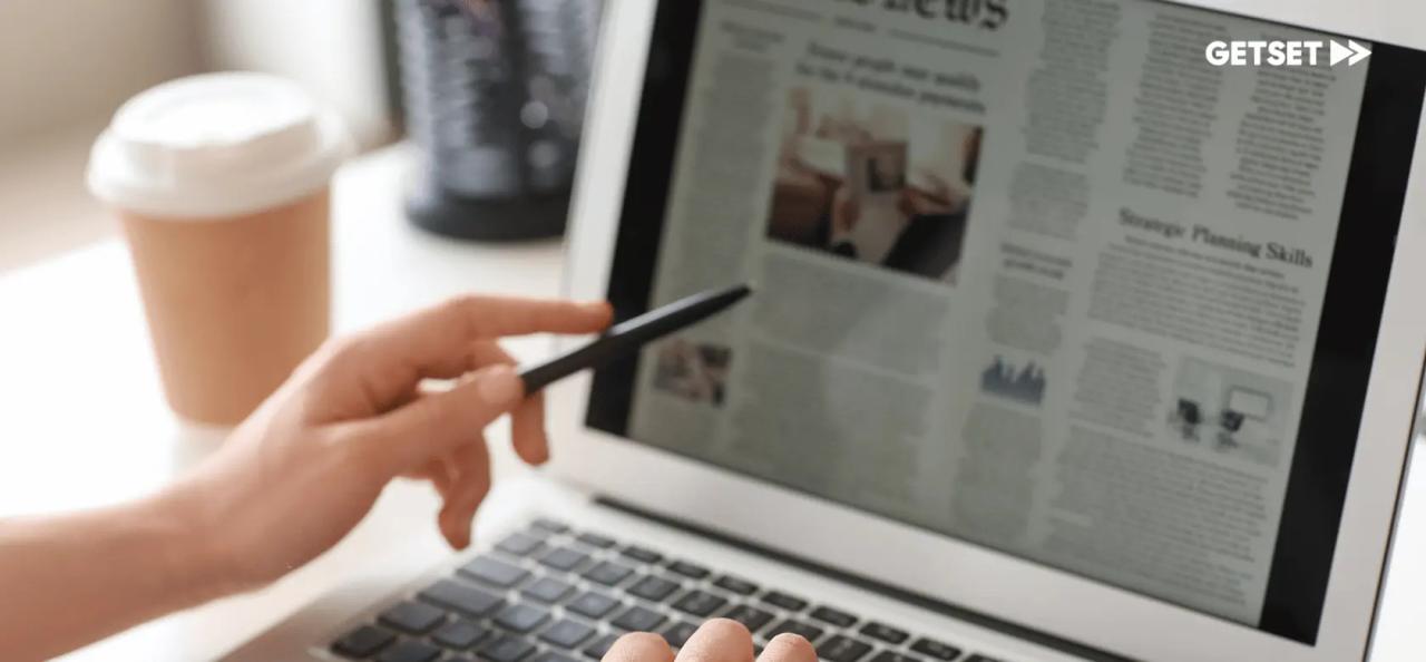 Hand holding a pen and pointing to a computer