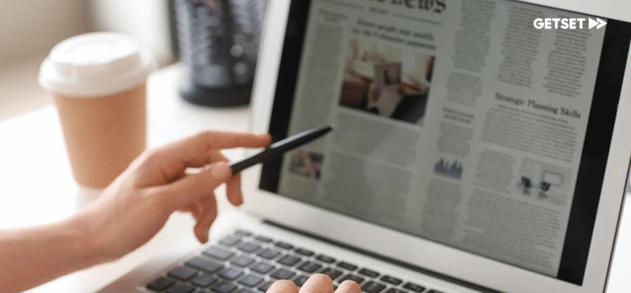 Hand holding a pen and pointing to a computer