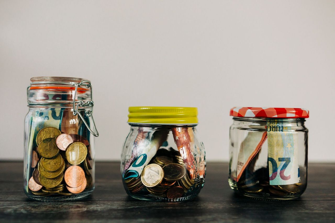 Three glass jars filled with different amounts of money
