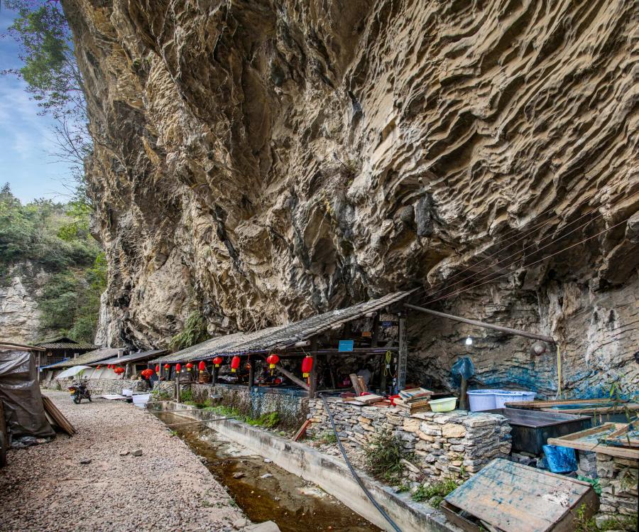 A row of classrooms with red lanterns under an overhanging rock cliff.