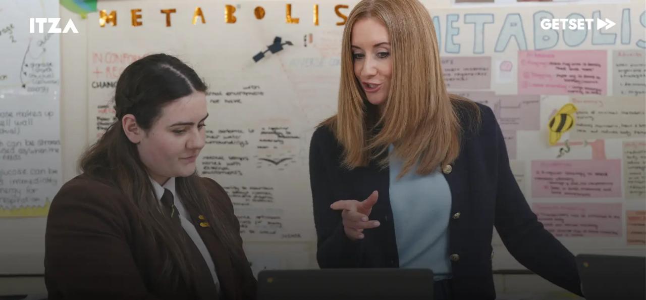 Teacher and students looking at a laptop.