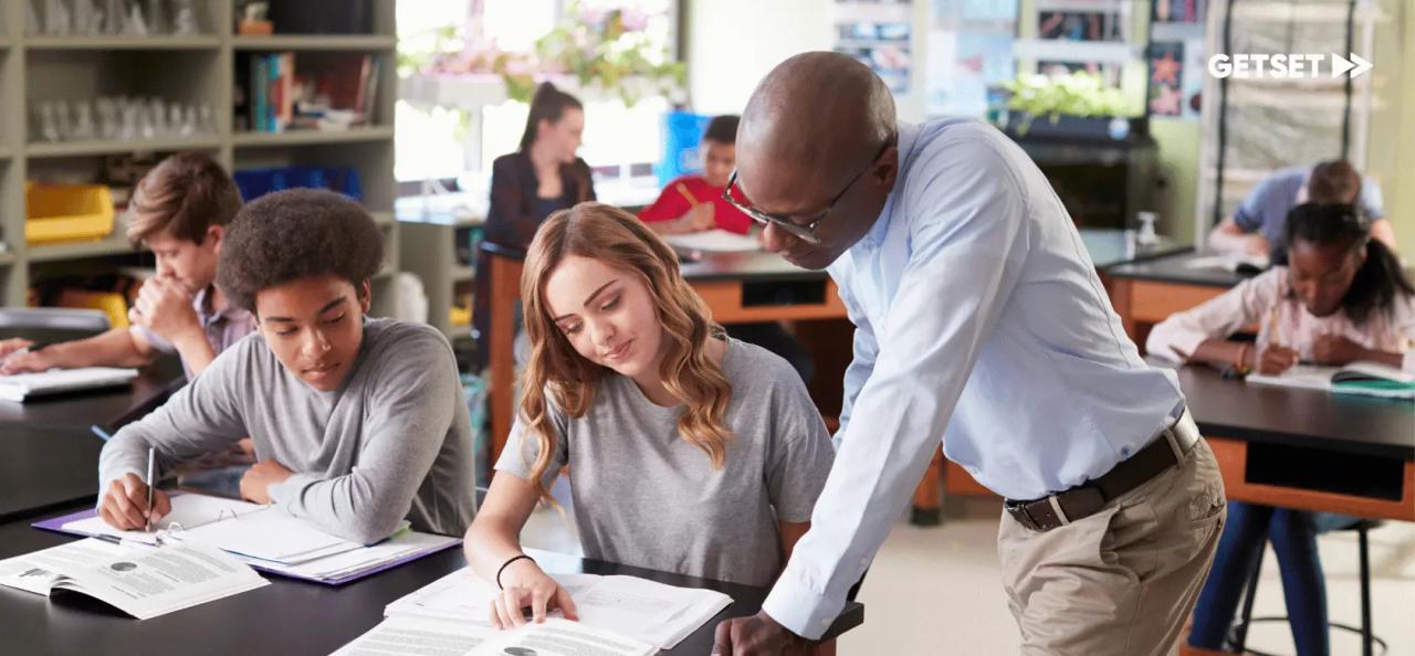 Teacher and students in the classroom looking at a book