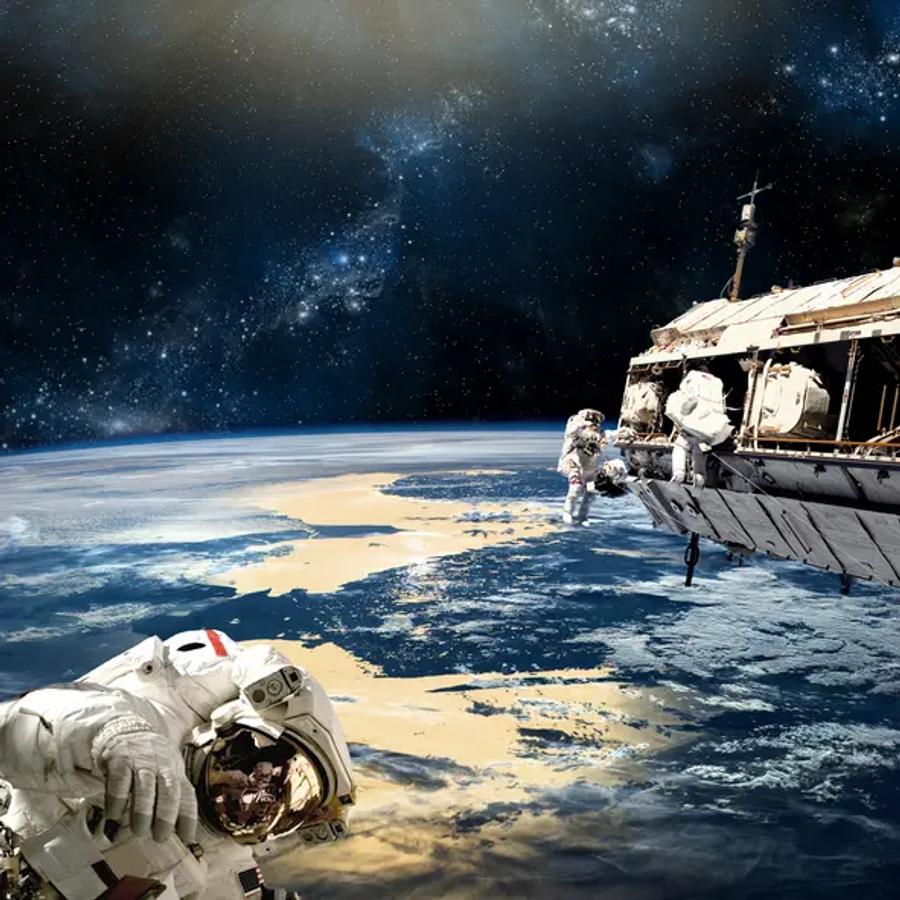 Two astronauts in white spacesuits working outside a space station, with Earth and its blue oceans and golden clouds below and stars above.