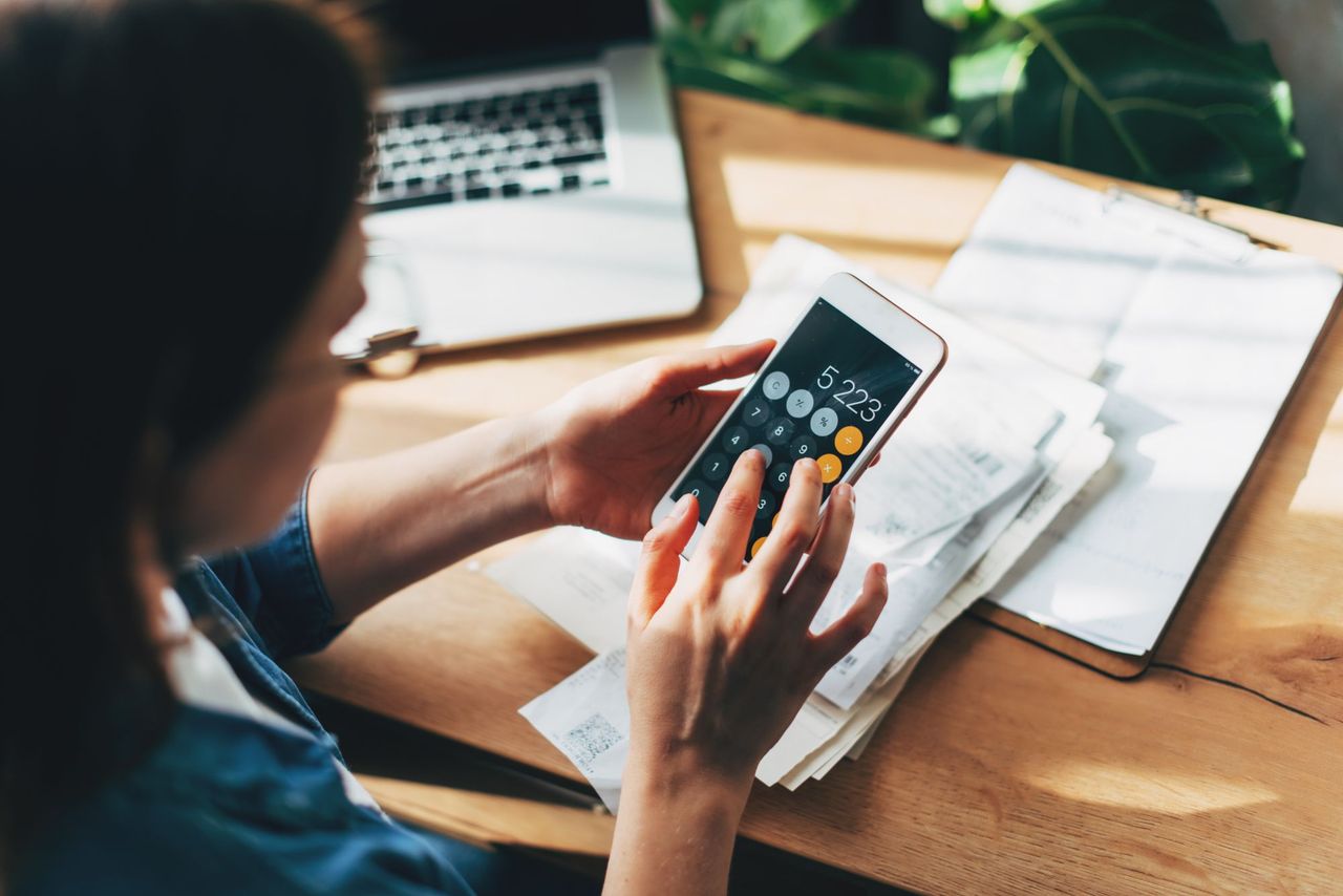 Woman calculating expenses on her mobile phone