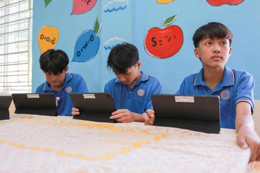 Minh (right) and his friends practice making videos on their schools' tablets.