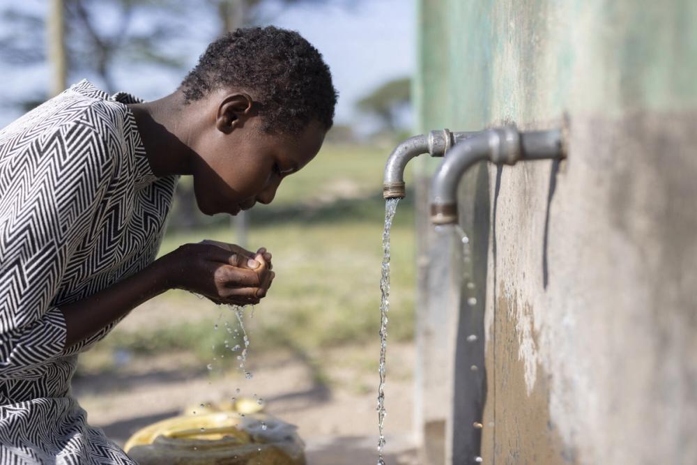 Agnes draws fresh water from ChildFund's newly-installed water point in her village.